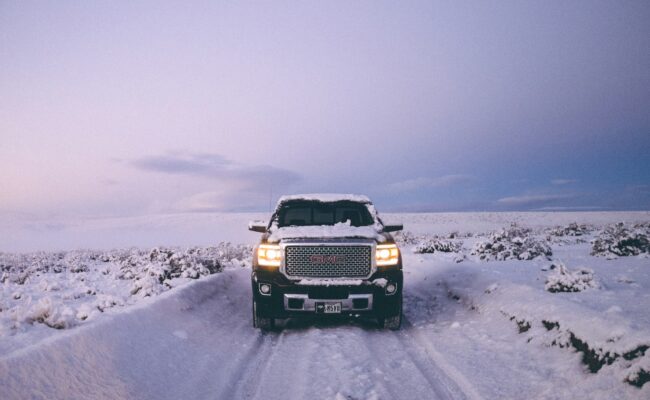 Black pickup truck driving on a snow-covered road in winter